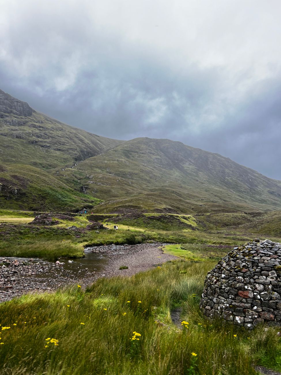 Rustic stone cabin amid green Scottish glen